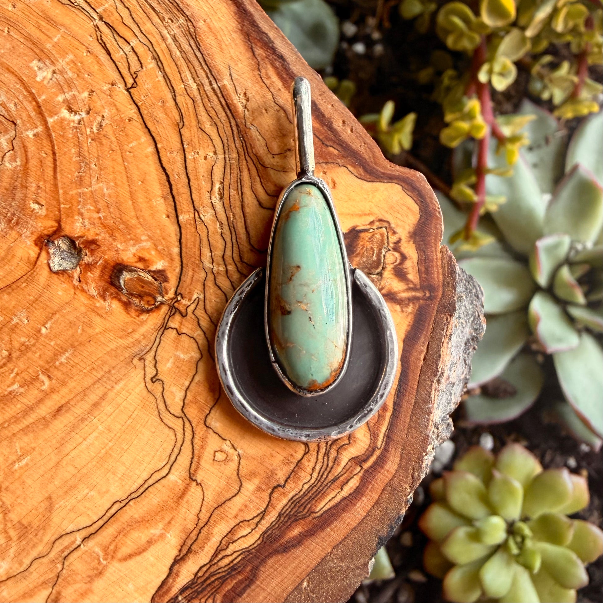 Turquoise pendant on wood and blurred green background