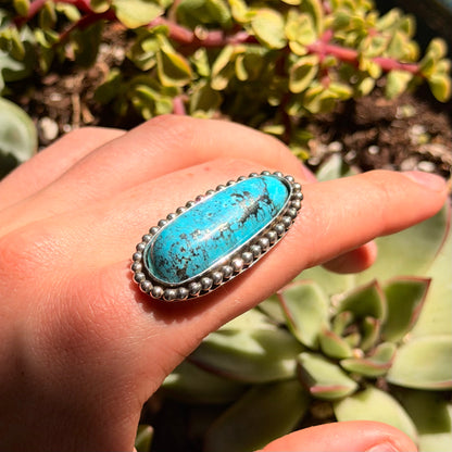 Turquoise ring with out shank , surrounded by green plants