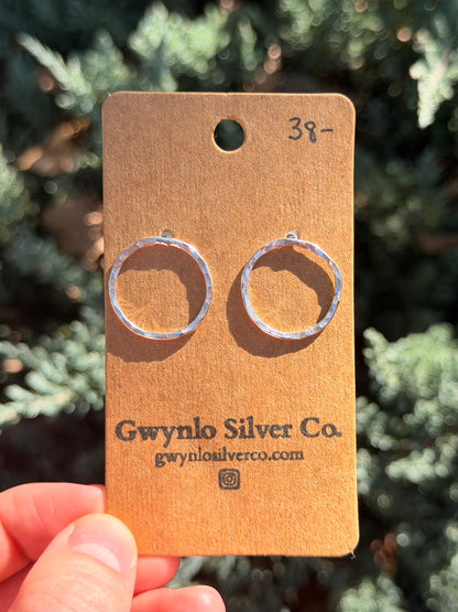 silver hoops on cardboard earring card with blurred green background.