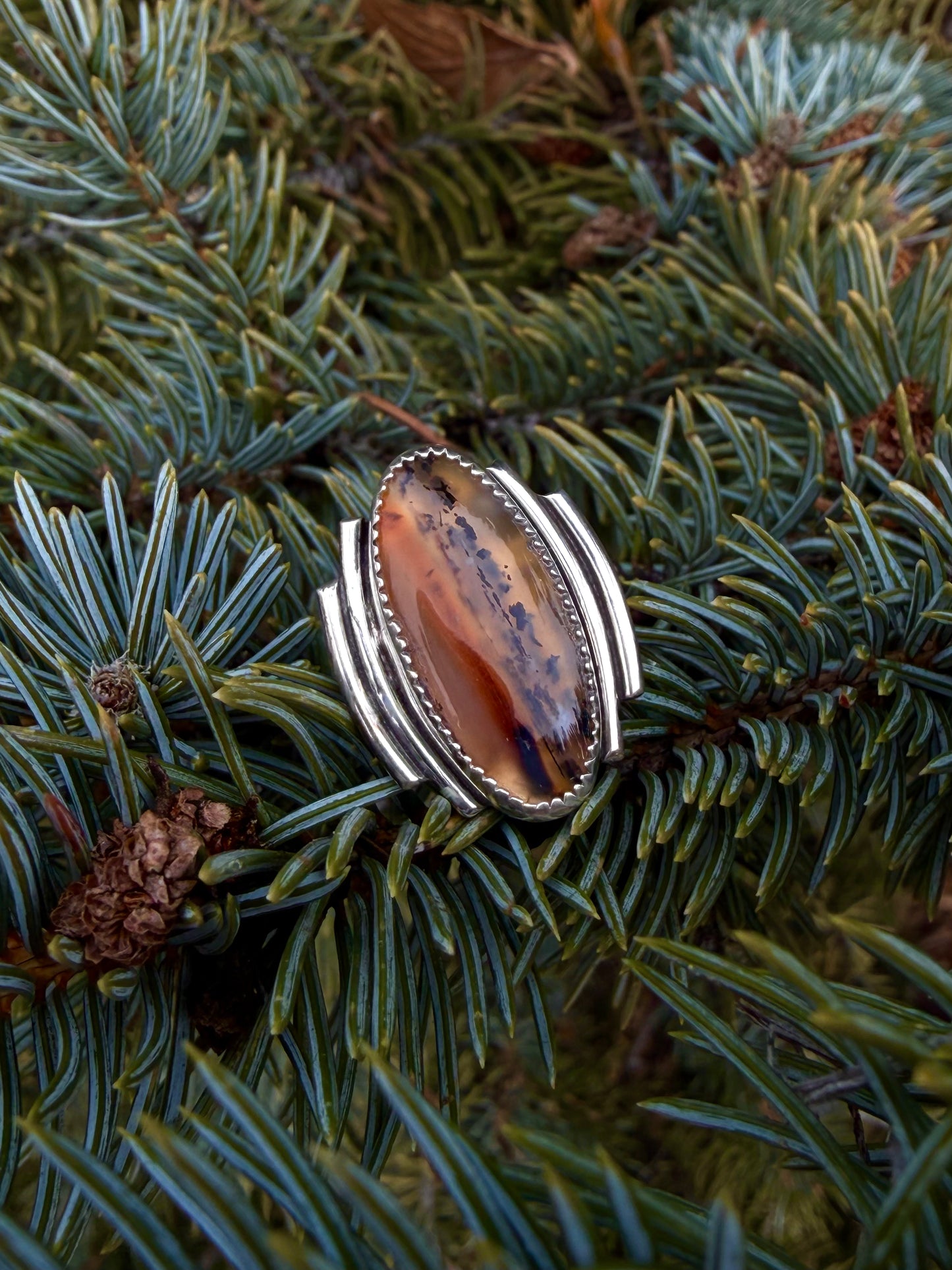 Silver ring with a large brown stone on a pine branch