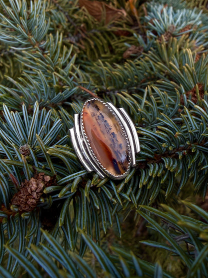 Silver ring with a large brown stone on a pine branch