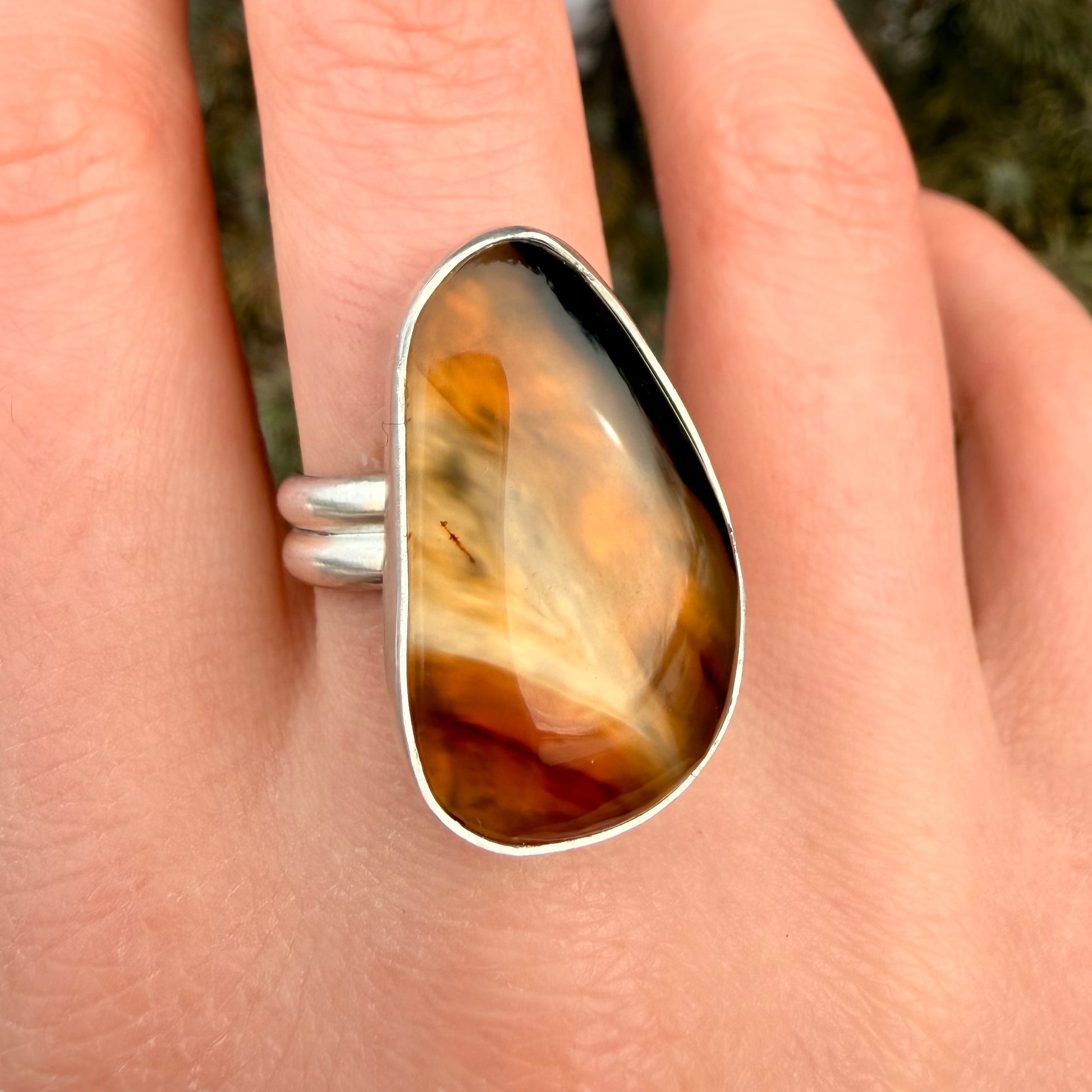 Ring with a large, brownstone-like gemstone on a person's finger.
