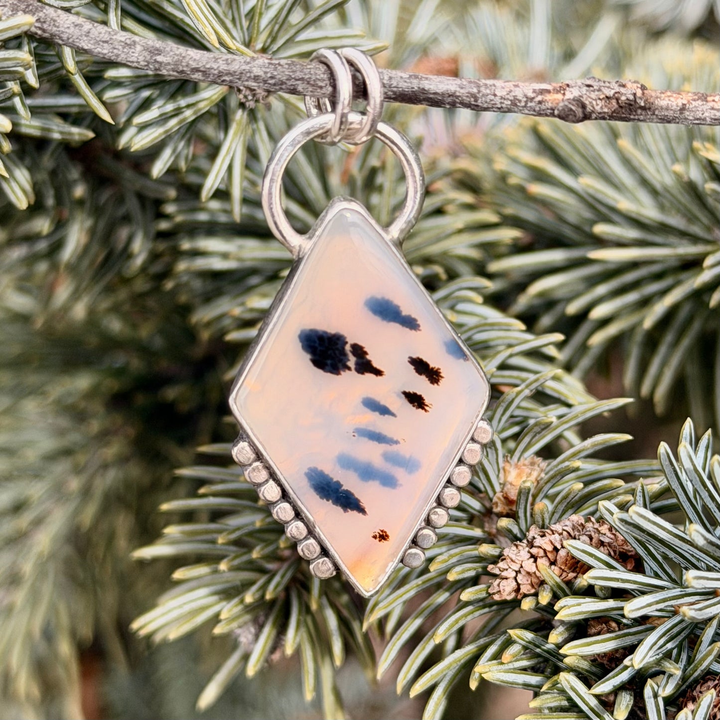Decorative pendant with abstract design hanging on a branch