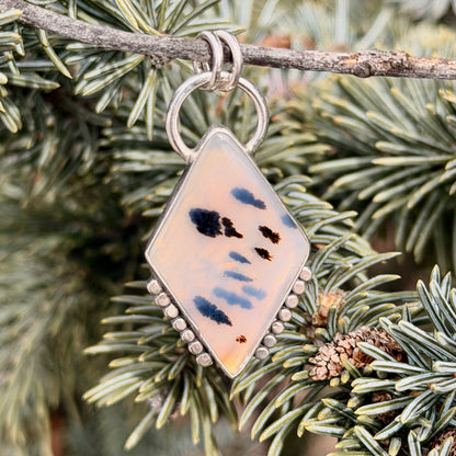 Decorative pendant with abstract design hanging on a branch