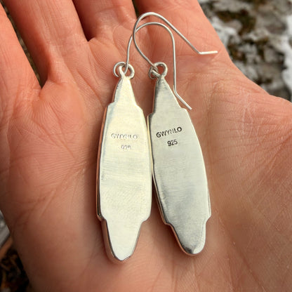 Silver earrings held in a hand with Gwynlo 925 stamp