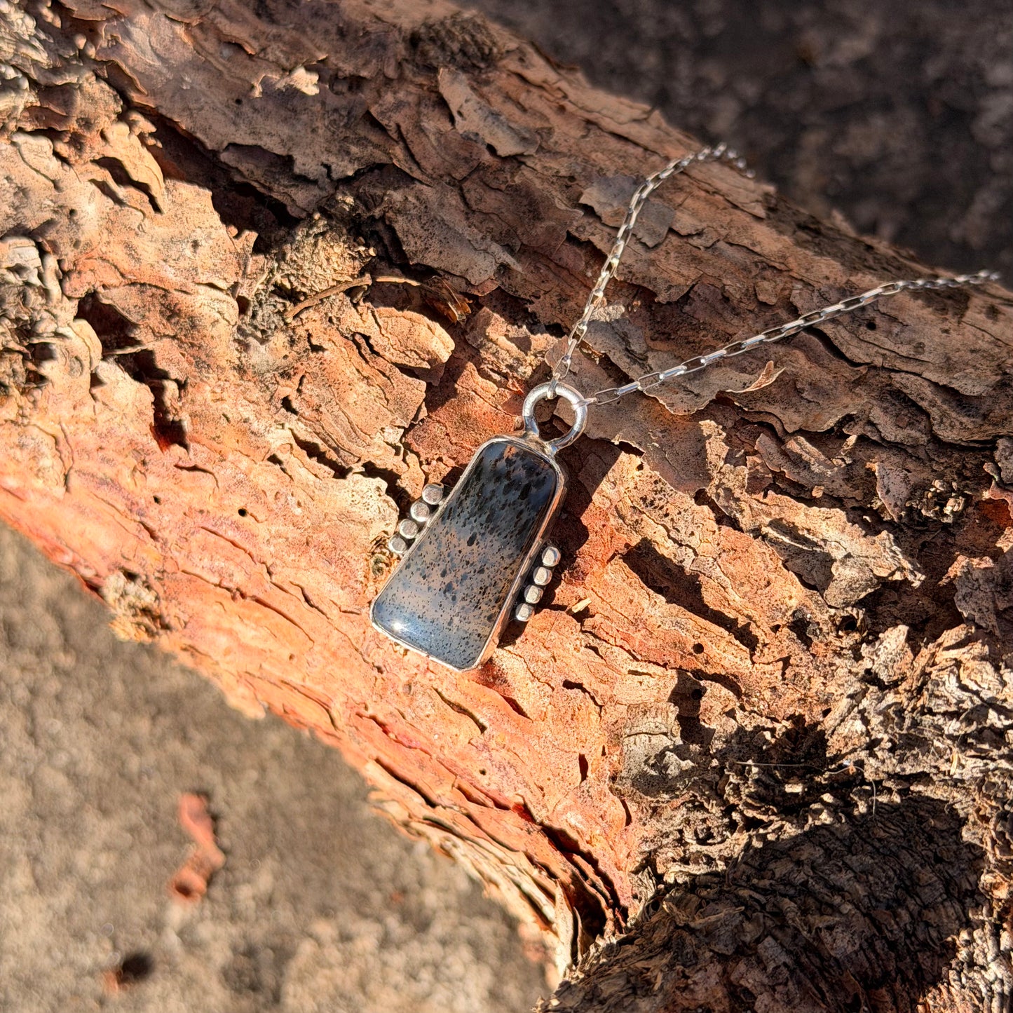 Silver pendant necklace on a piece of wood