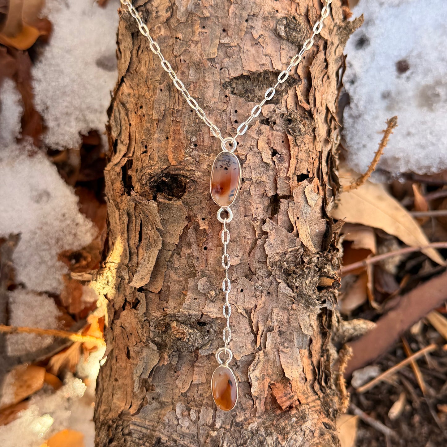 Necklace with pendant on a tree trunk in a natural setting