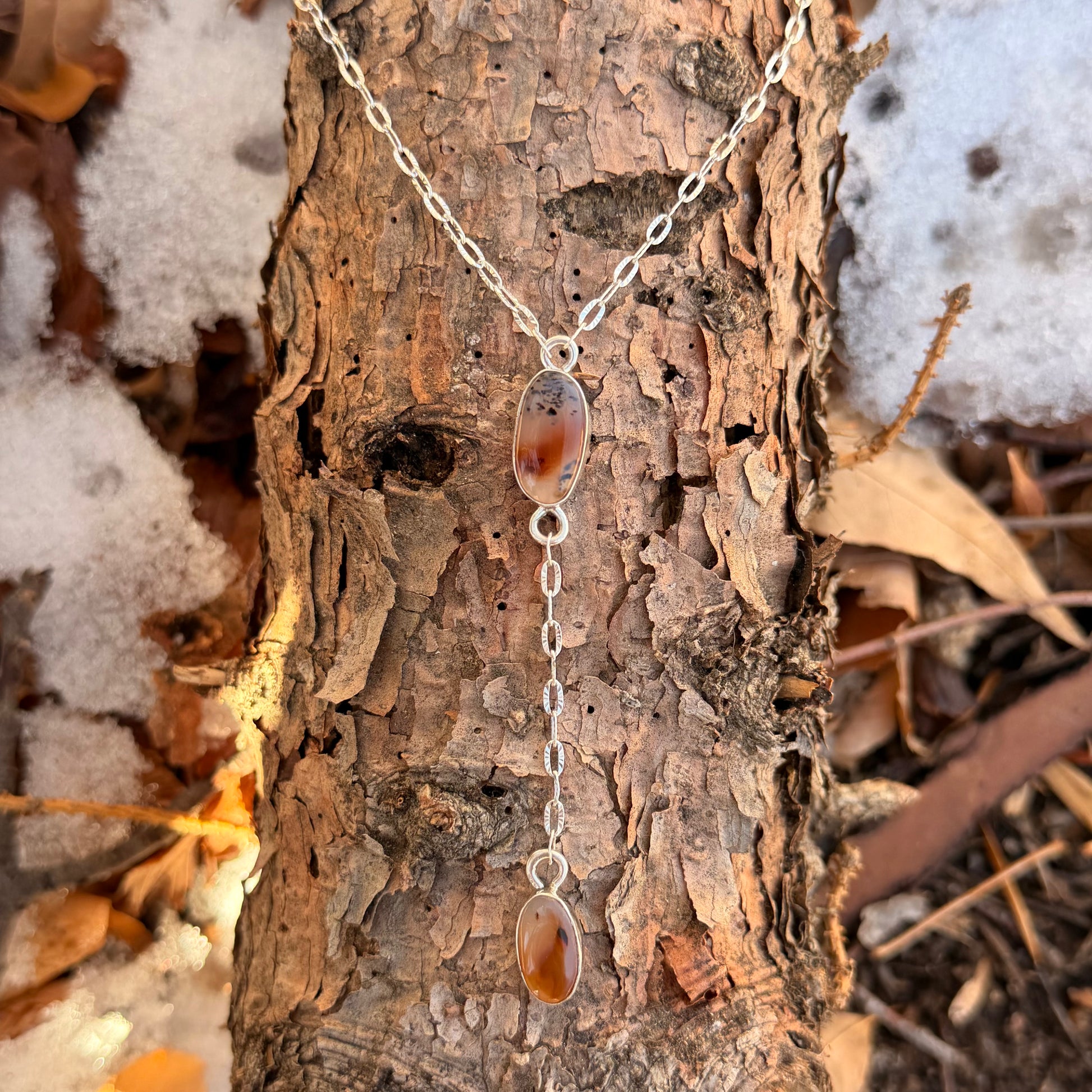 Necklace with pendant on a tree trunk in a natural setting