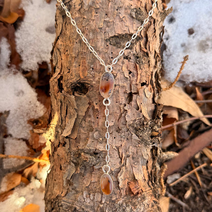 Necklace with pendant on a tree trunk in a natural setting